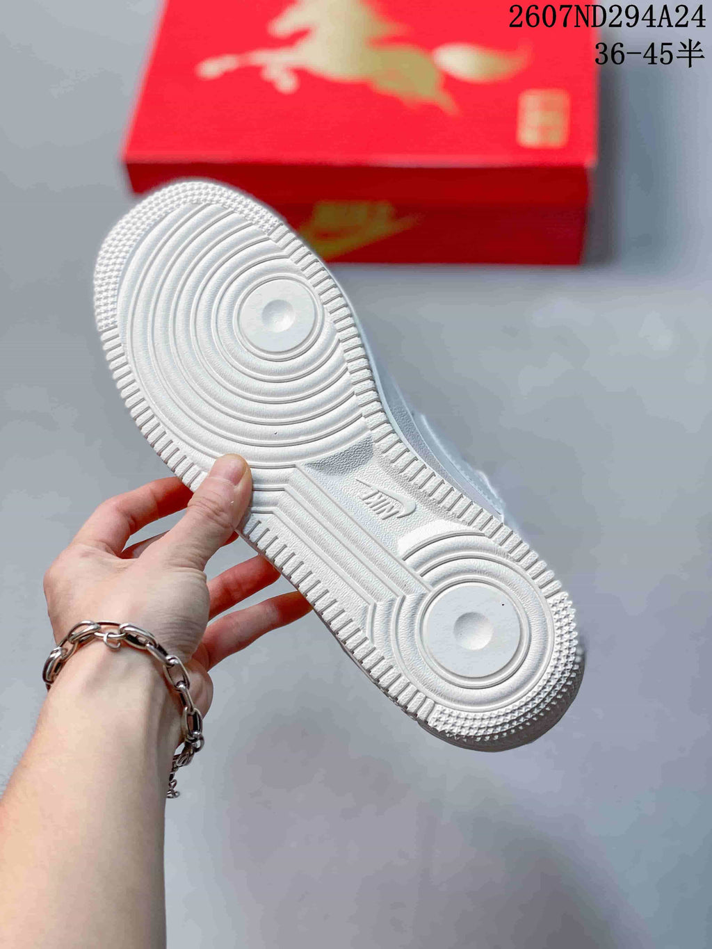 Underside view of the white sneaker showing the circular traction pattern and textured rubber outsole.