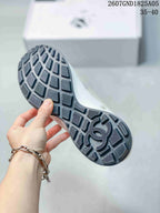 Close view of the black patterned outsole with geometric tread blocks and a central double-C motif.