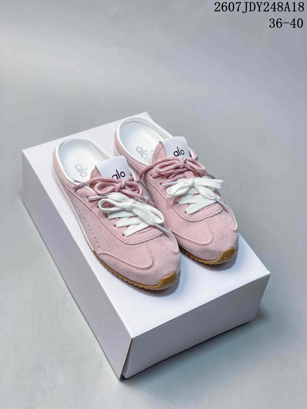 Pink alo Sunset mule sneakers with white and pink laces displayed on a white shoebox.