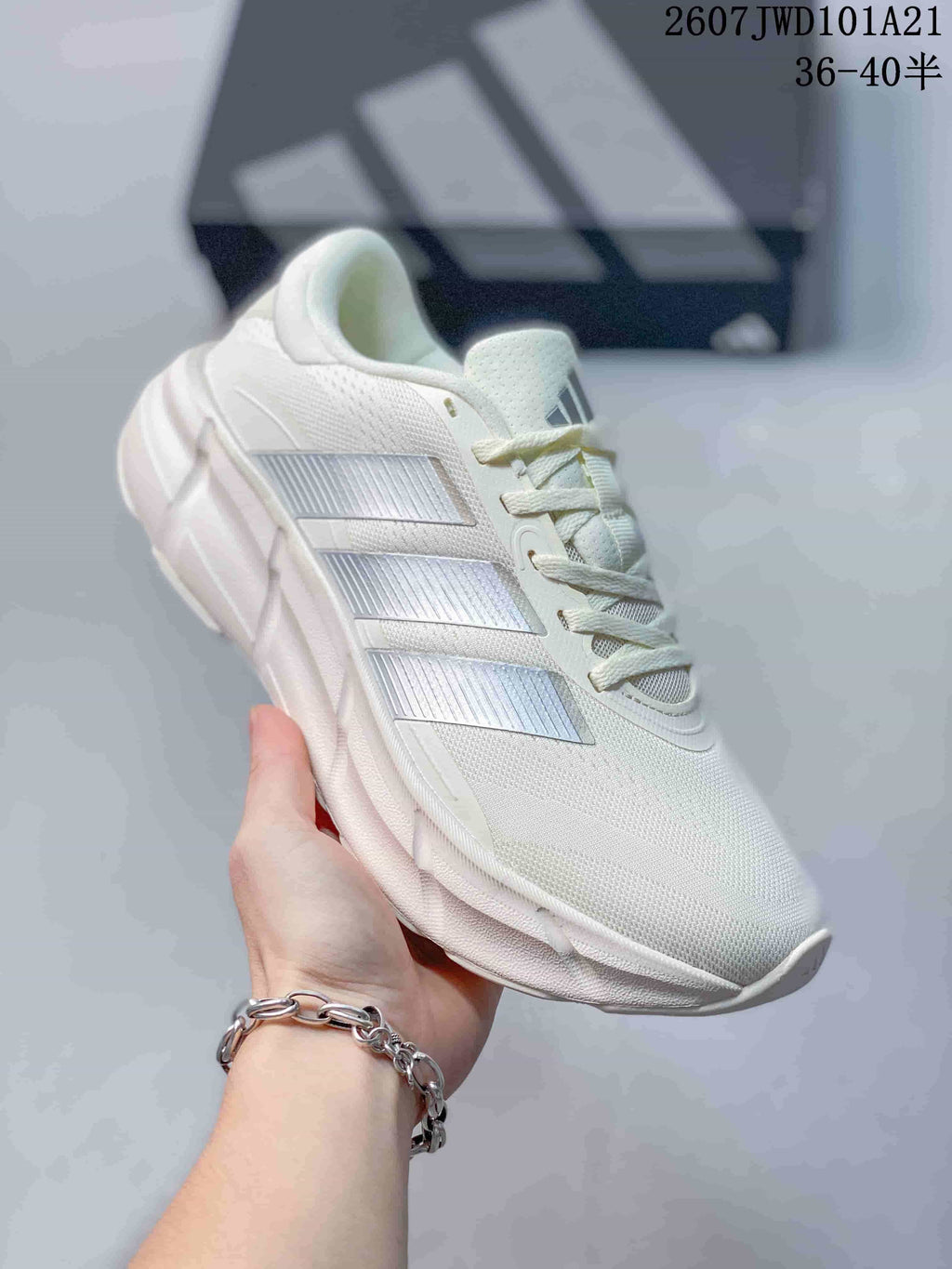 Angled side view of the white Adidas sneaker showing the textured upper, silver three-stripe panels and cushioned sole.
