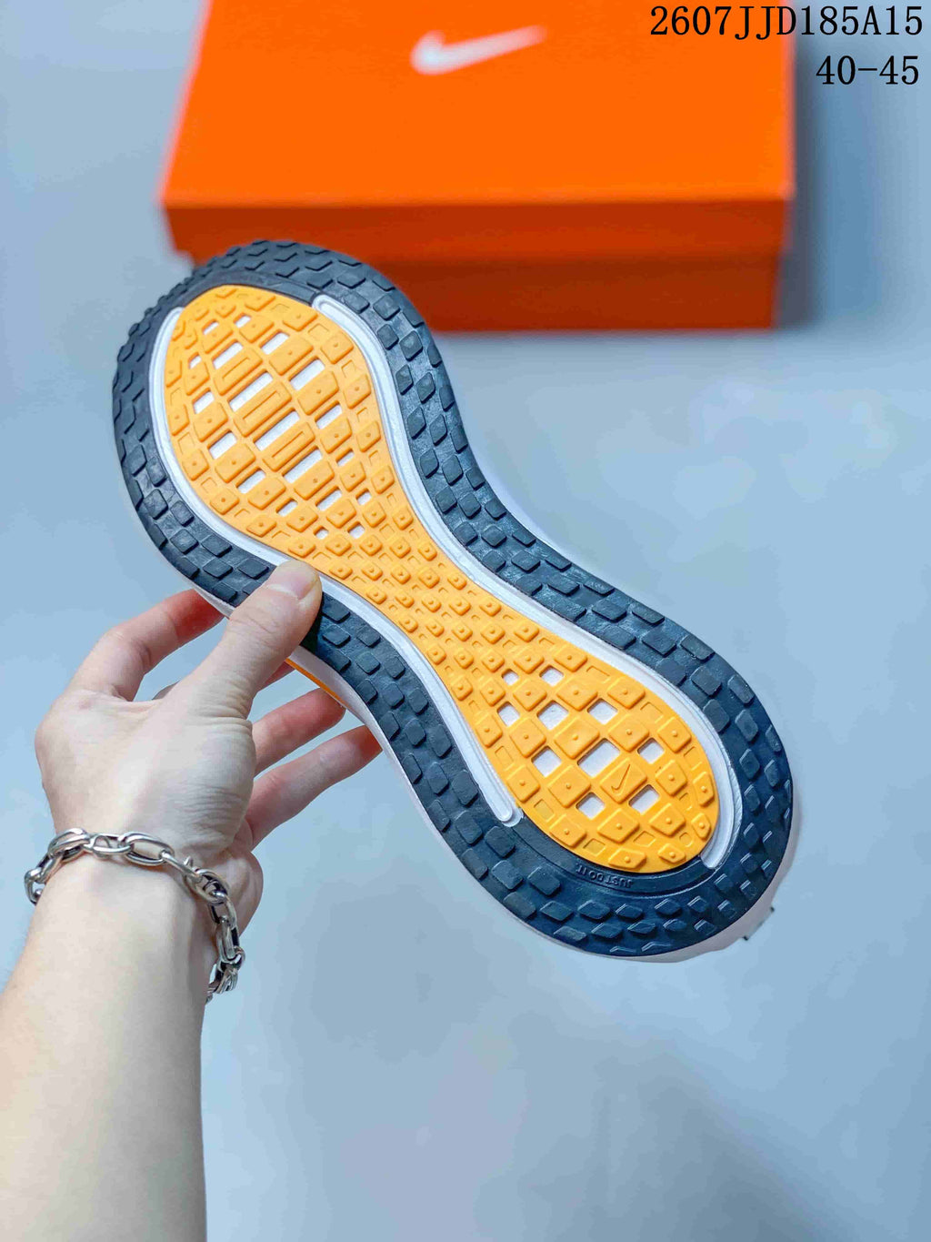 Close-up of the patterned rubber outsole with orange central tread and dark outer traction sections.