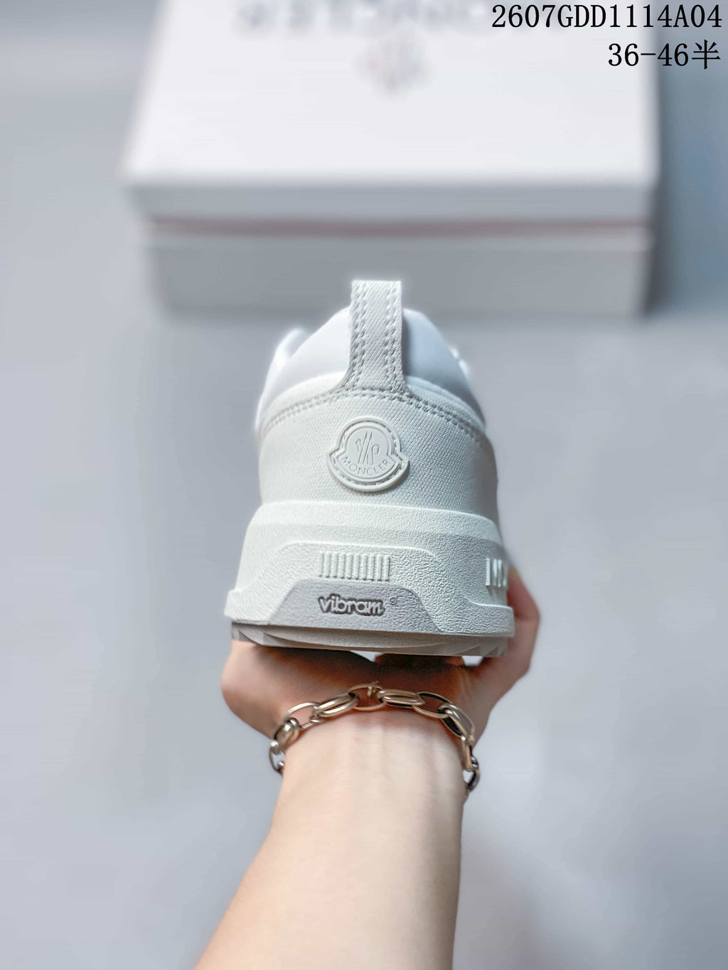 Rear view of the white sneaker showing the Moncler heel emblem, pull tab and Vibram branding on the sole.