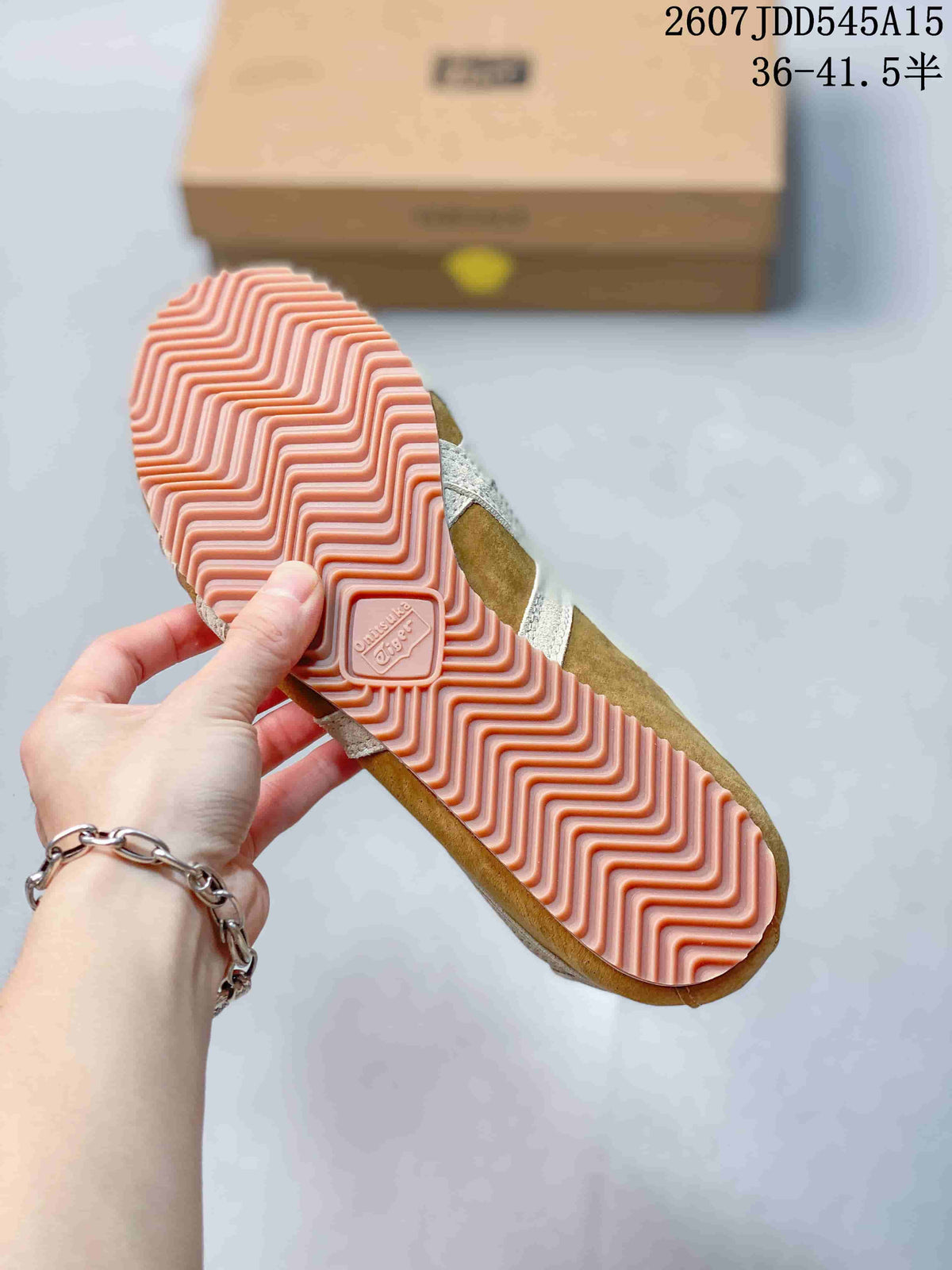 Close-up of the pink rubber outsole showing its repeating wavy tread pattern and Onitsuka Tiger logo detail.