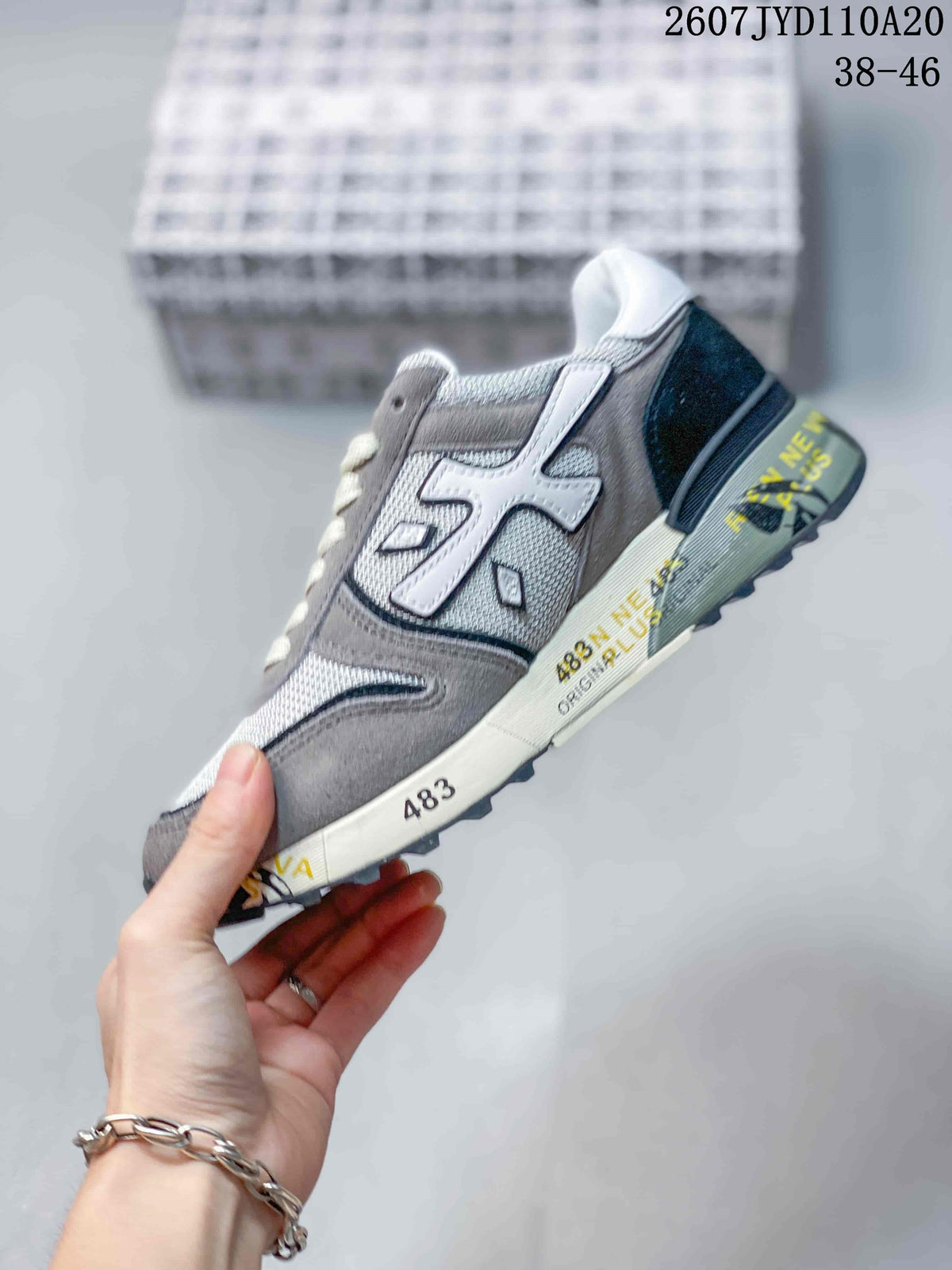 Side profile of the grey and white sneaker showing the layered upper, contrasting side emblem and graphic midsole.