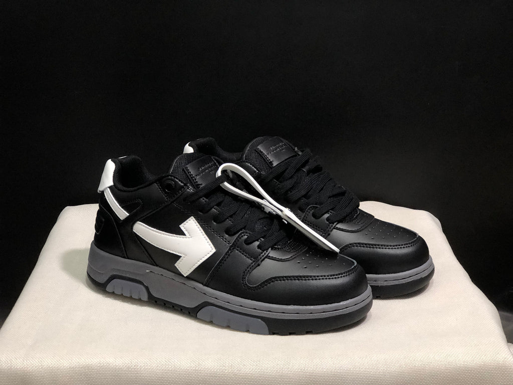 Three-quarter view of the black and white low-top sneaker pair with white lace accessories and gray layered midsoles.