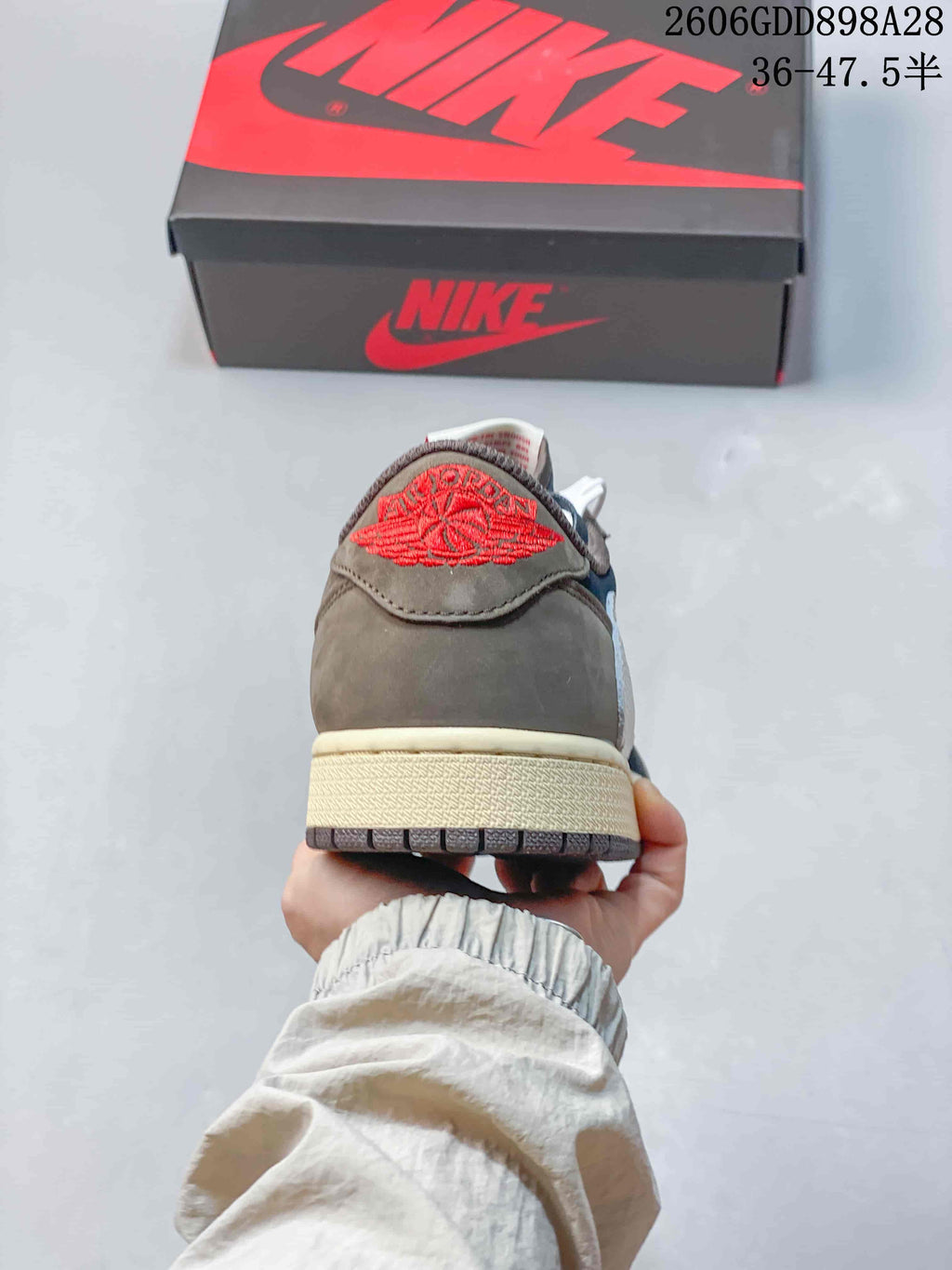 Rear view showing a taupe heel panel and red embroidered detail