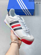 White Adidas Samoa sneaker with dark and red side stripes and a red outsole section.