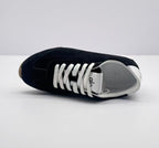 Top view of one black sneaker showing the lace arrangement, white tongue, and white interior.