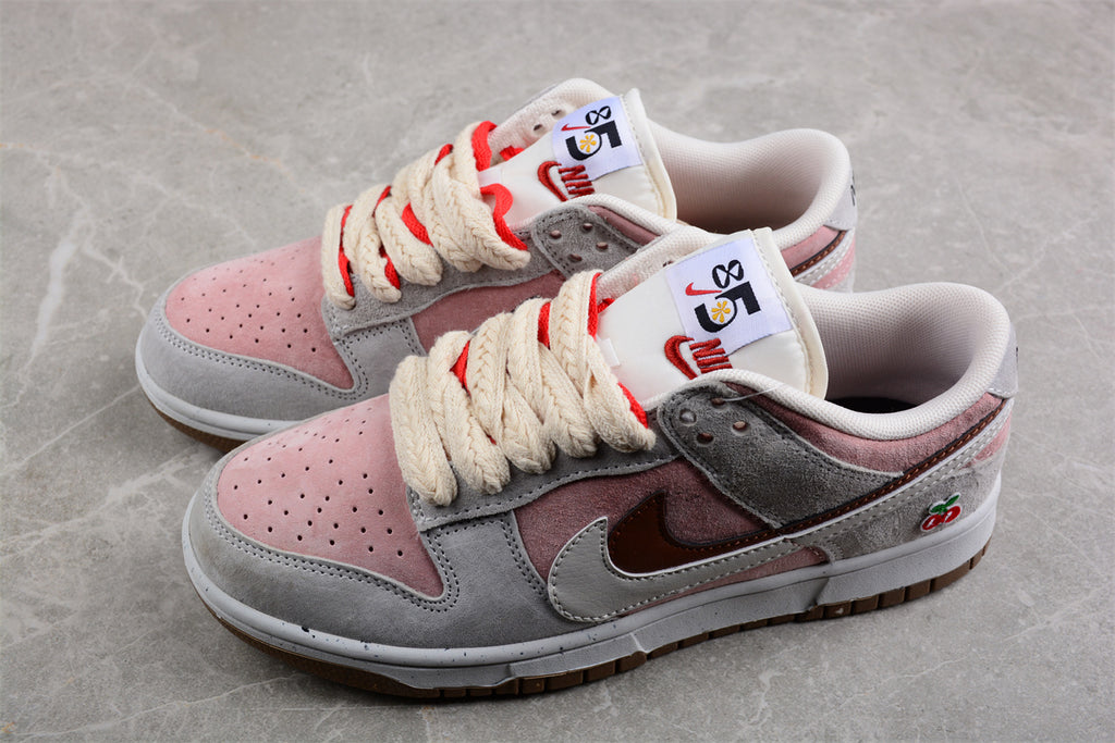 Pair of pink, white, and gray low-top sneakers with brown Swooshes, cream laces, and cherry heel details.