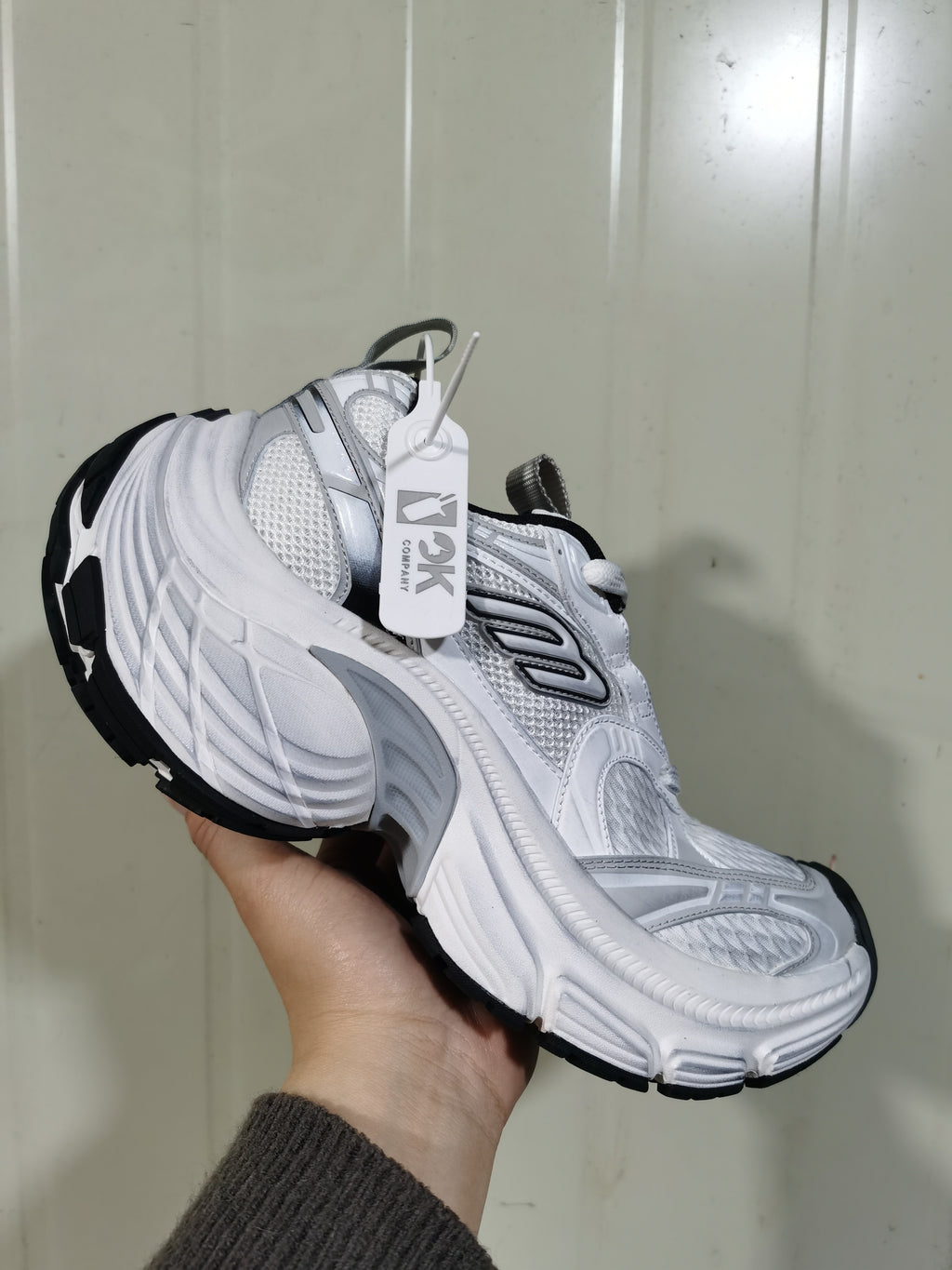 Close angled view of the white and black 9110 sneaker showing mesh panels, layered overlays, padded collar, and chunky sole.