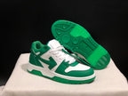 Angled view of one green and white sneaker with the outsole facing upward, showing its patterned green tread.