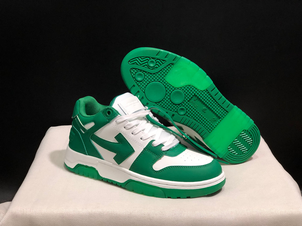 Angled view of one green and white sneaker with the outsole facing upward, showing its patterned green tread.