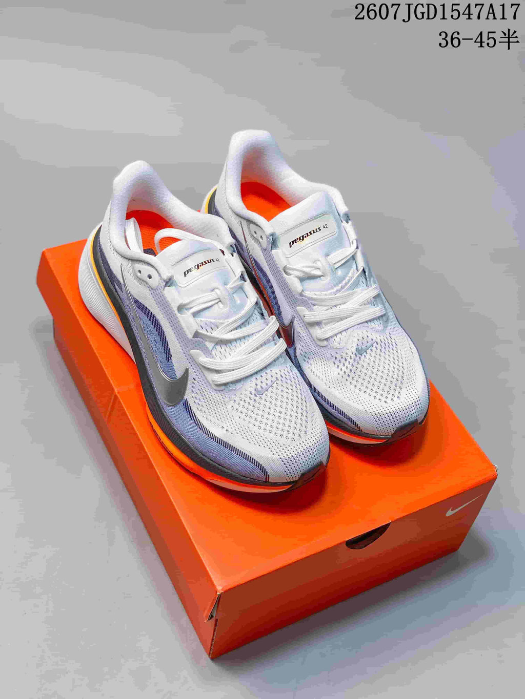 Nike Pegasus 42 running shoes shown from above on an orange shoebox, with white uppers, blue detailing and orange accents.