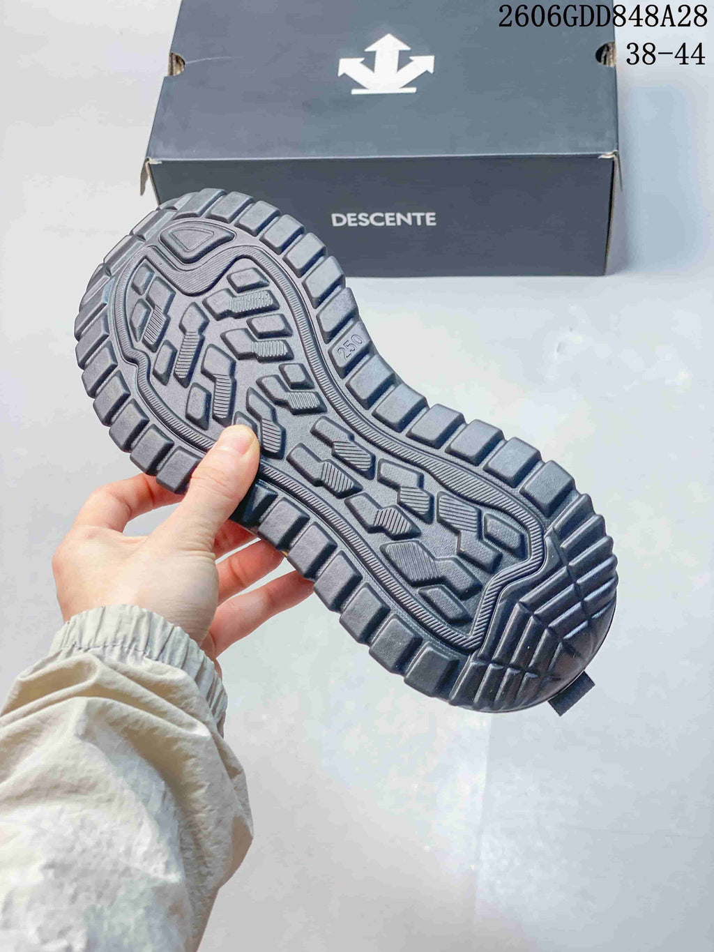 Close view of the shoe's lugged outsole beside a DESCENTE box; image states sizes 38–44 and style code 2606GDD848A28.