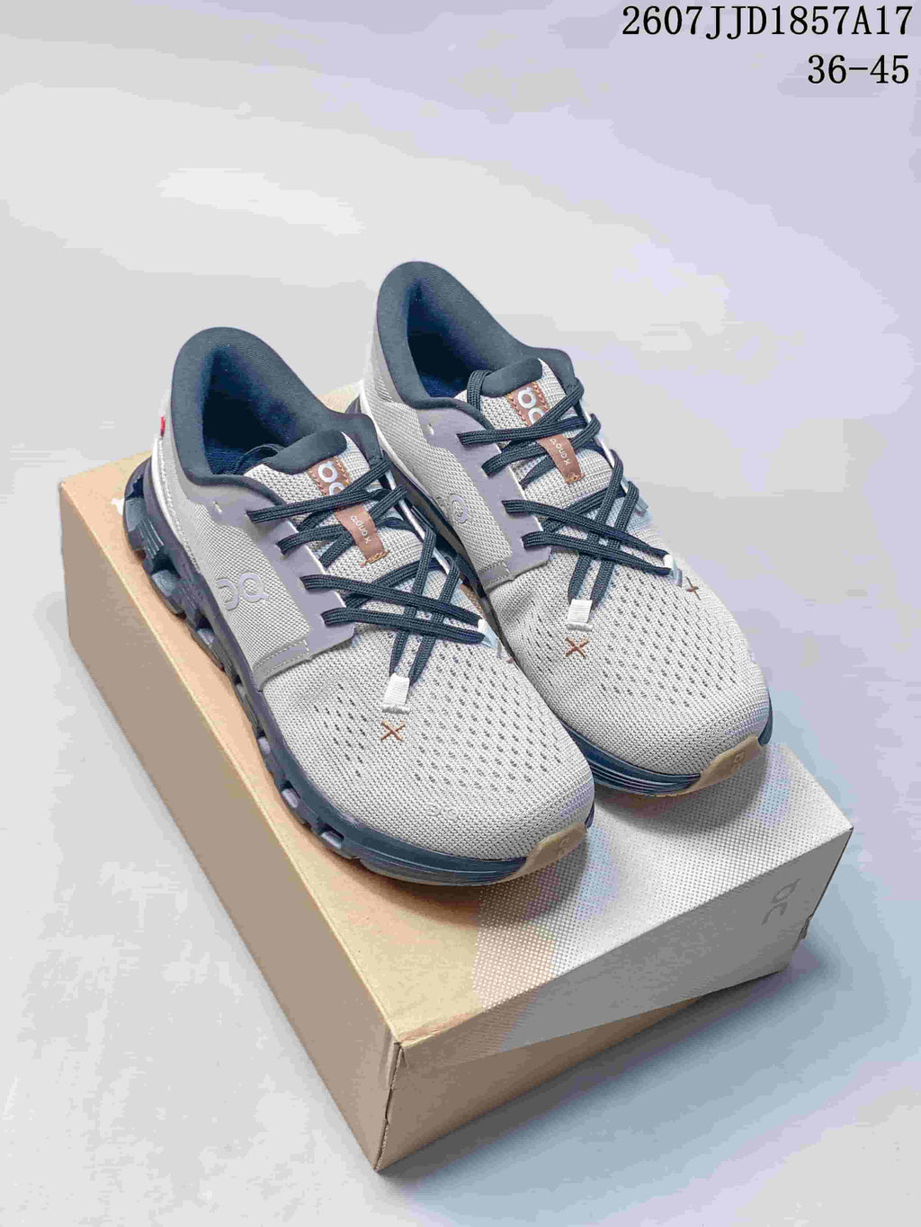 Gray and white On Cloud X 4 sneakers displayed on a shoebox.