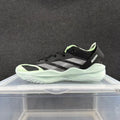 Side view of a black Adidas Adizero sneaker with light-colored stripes, pale green accents, and a light sculpted sole