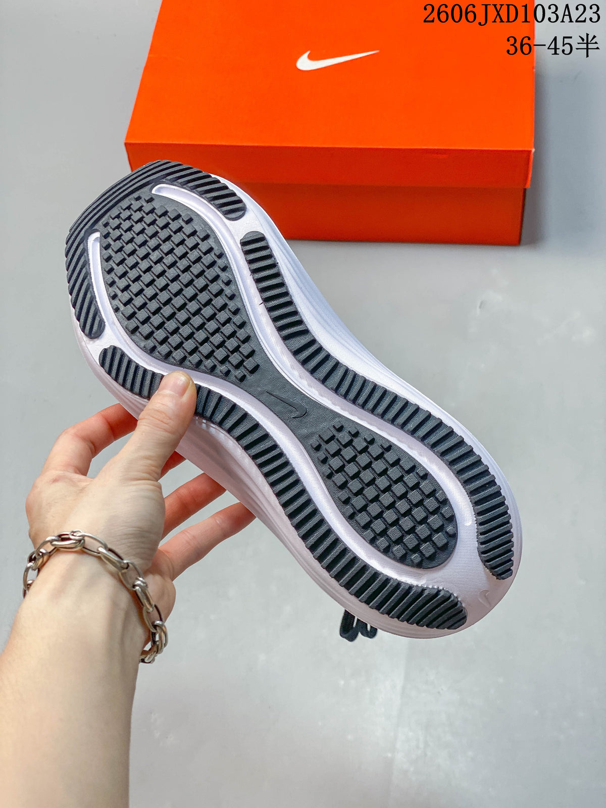 Underside of a running shoe showing a black patterned outsole and white midsole