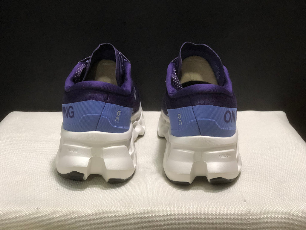 Rear view of the purple and blue On Cloudmonster 3 shoes showing the padded heel collars and white midsoles.
