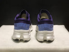 Rear view of the purple and blue On Cloudmonster 3 shoes showing the padded heel collars and white midsoles.