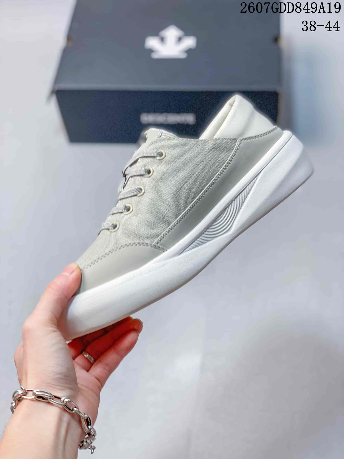 Side view highlighting the light gray upper, white overlays, stitched panels, and raised sole.