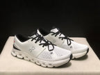 Three-quarter view of the pair of Ivory and Black On Cloud X4 sneakers.