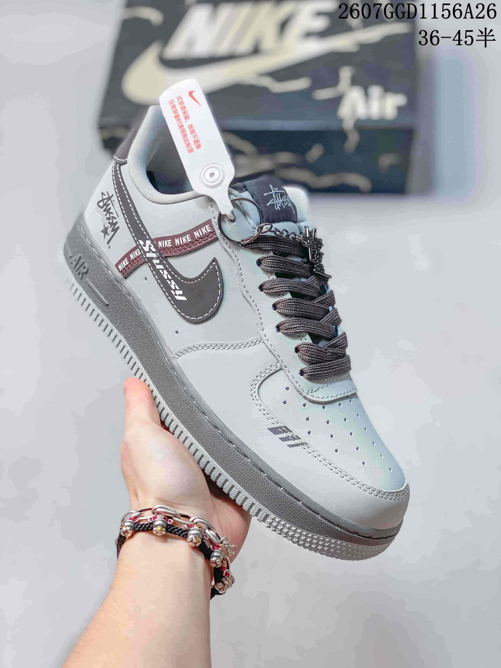 Angled side view showing the gray upper, dark Swoosh, graphic heel accents, decorative laces, and rubber outsole.