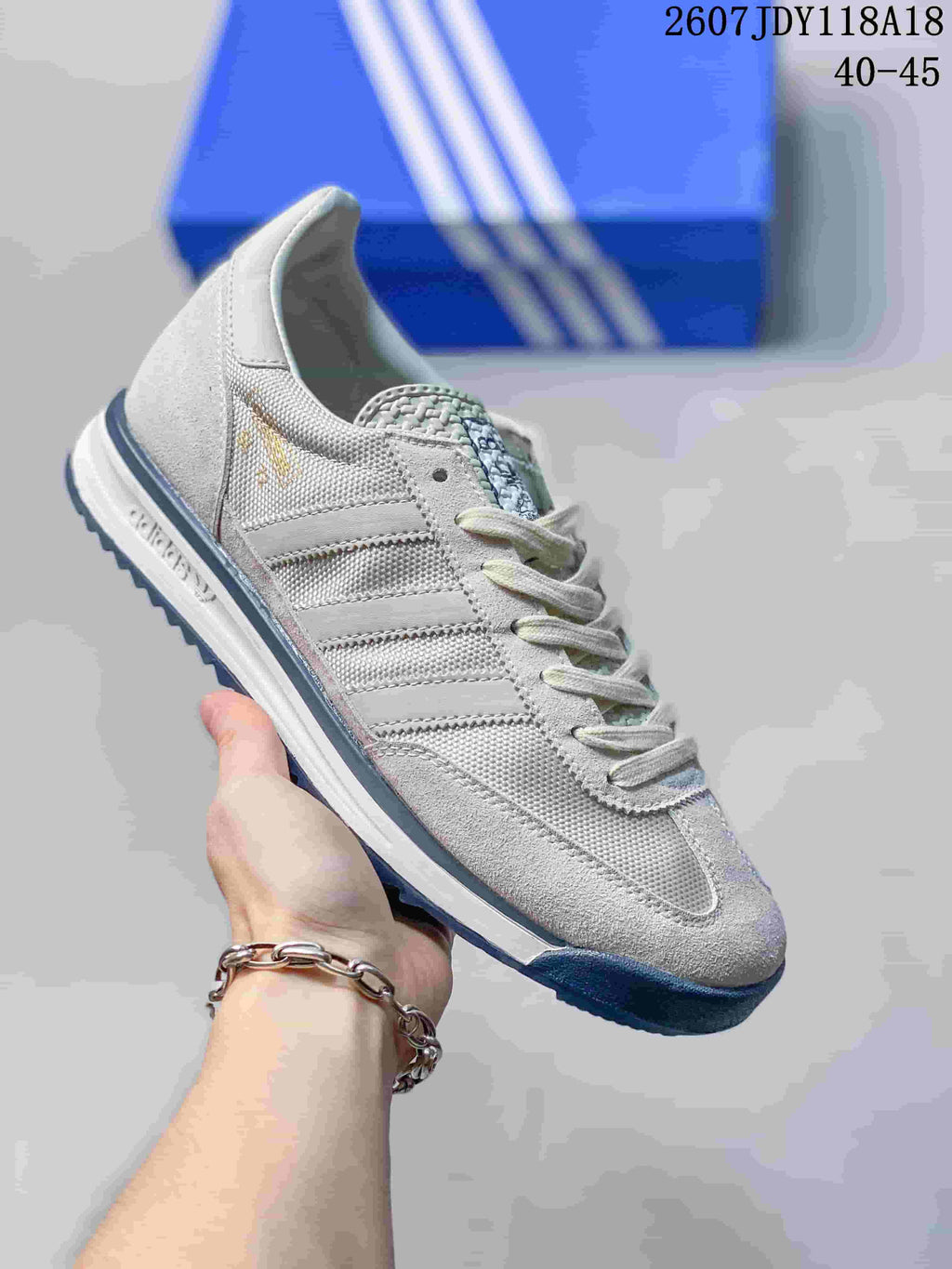 Light gray and white adidas SL 72 sneaker with subtle gold branding and a dark blue outsole.