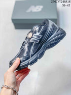 Side profile of a black and gray New Balance sneaker showing the large side logo, mesh panels, and layered sole.