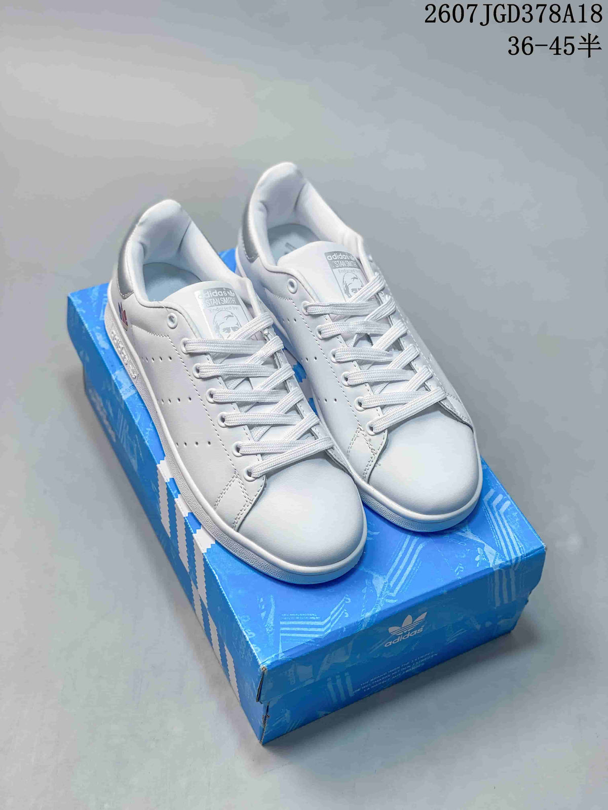 Pair of white Adidas Stan Smith sneakers displayed on a blue Adidas shoebox.