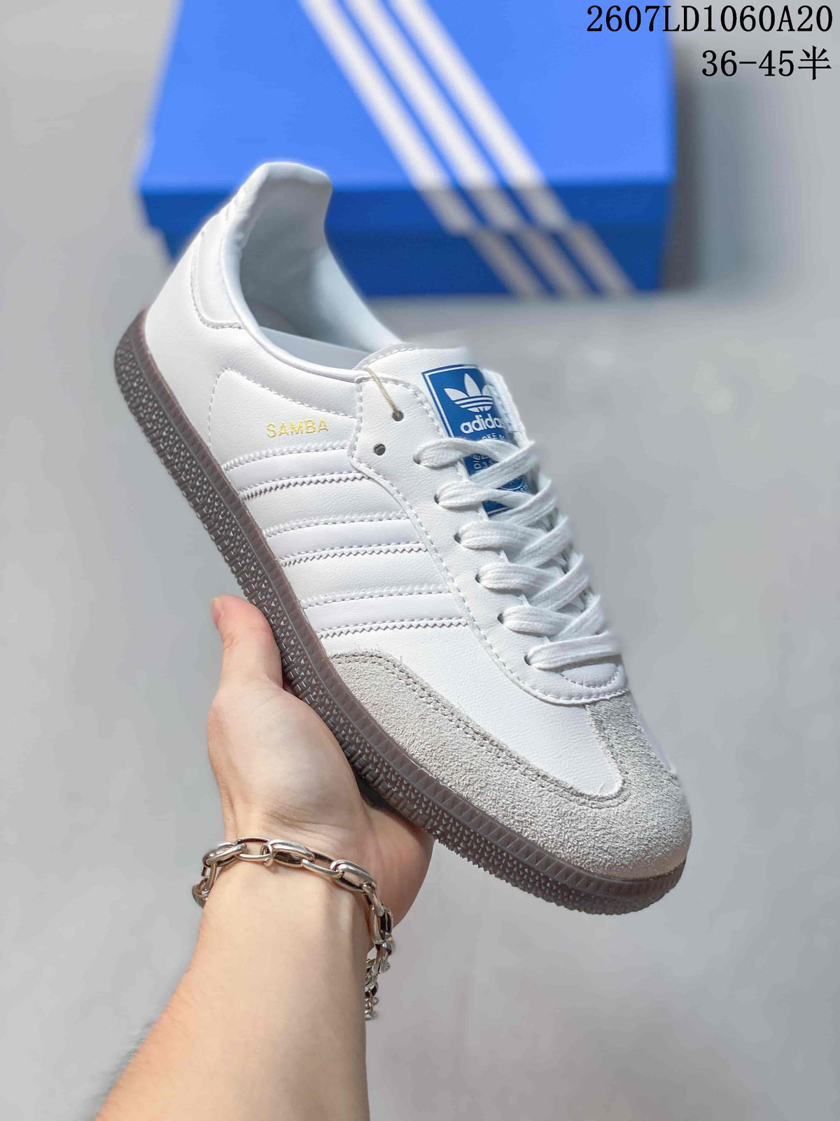 Angled side view of the white sneaker showing SAMBA lettering, three stripes, and gray toe detailing.