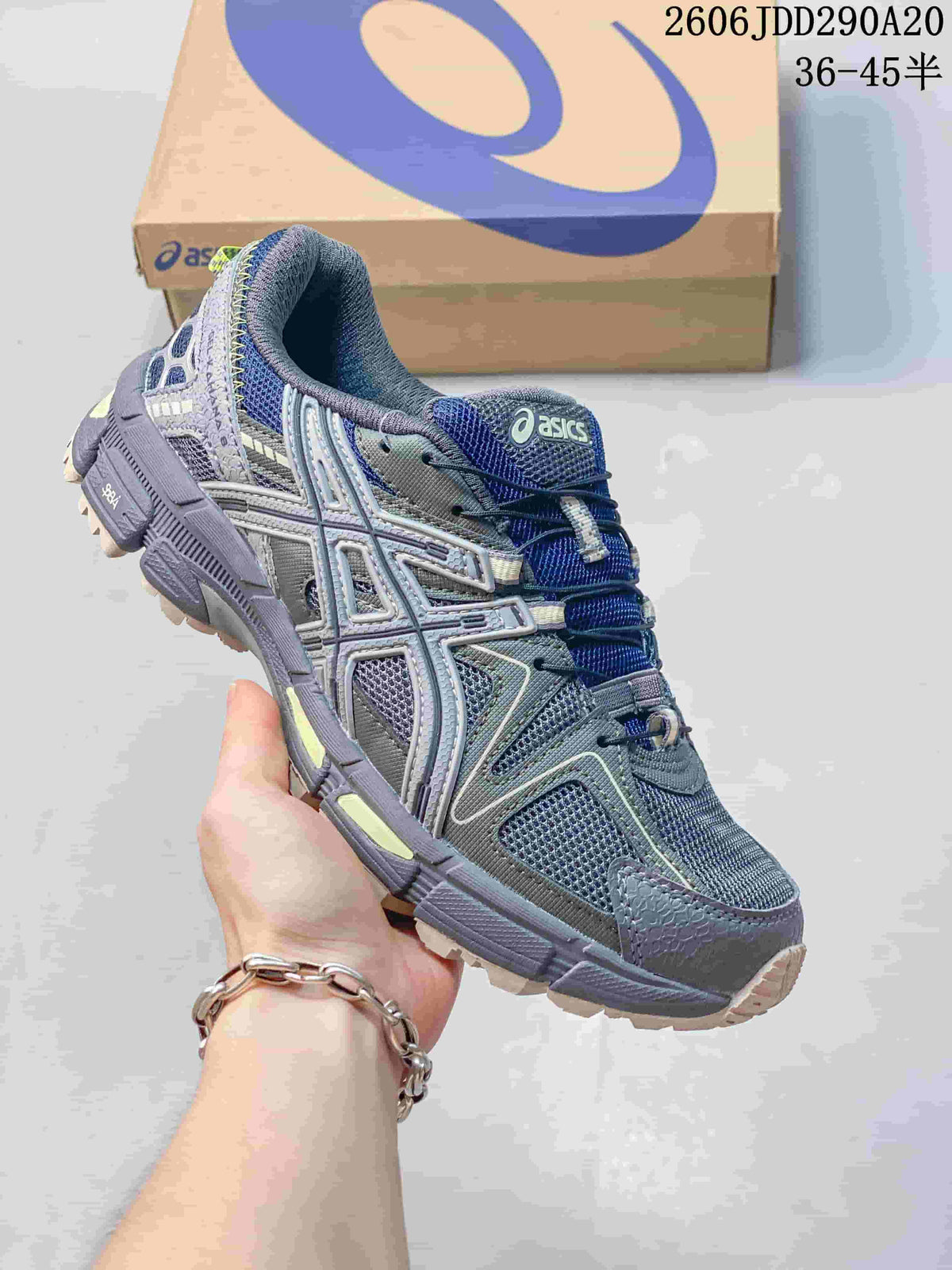 Grey and navy ASICS Gel-Kahana 8 sneaker held in front of a shoebox