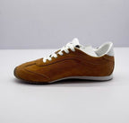 Opposite side view of the brown low-top sneaker with white laces and layered stitched panels.