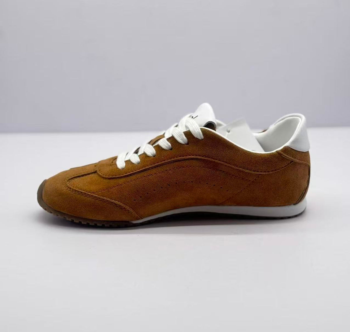 Opposite side view of the brown low-top sneaker with white laces and layered stitched panels.