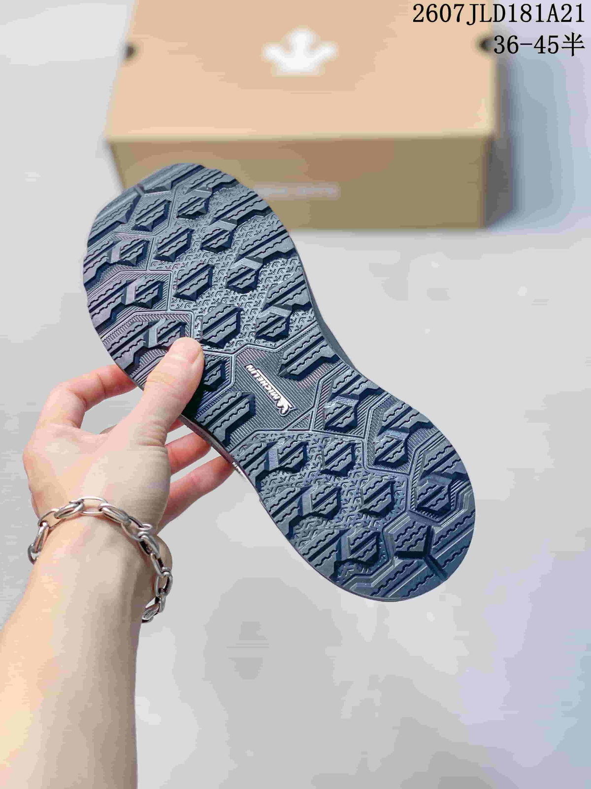Underside view showing the sneakers' patterned black outsole and geometric tread.