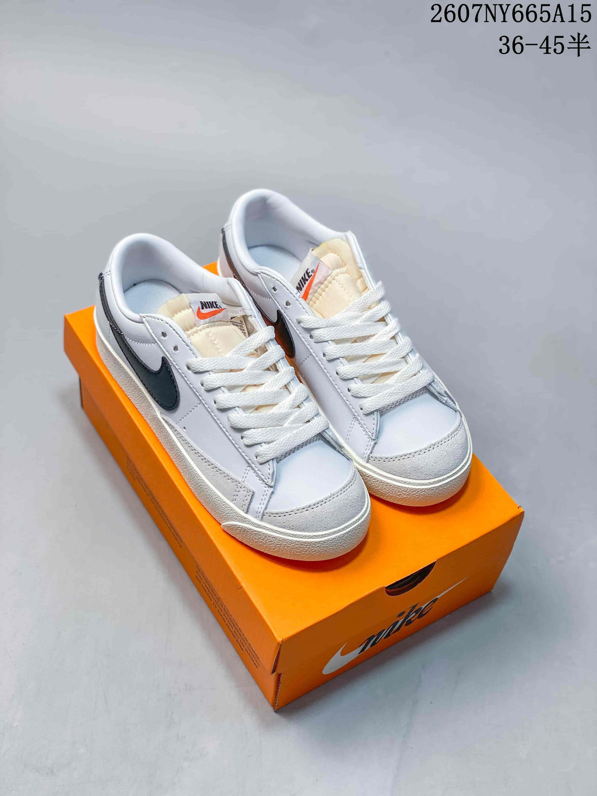 Pair of white and black Nike low-top sneakers displayed on an orange shoebox.