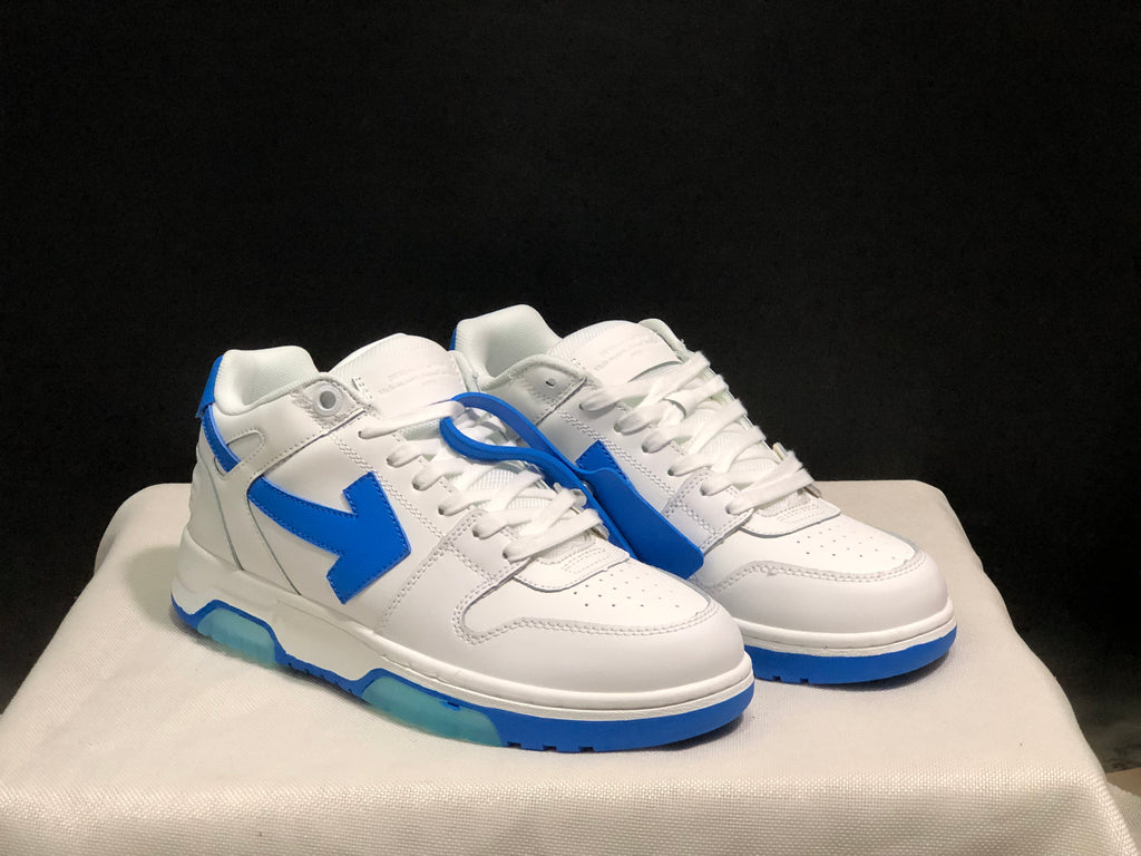 Three-quarter front view of the paired white and blue low-top sneakers with blue tag accessory.
