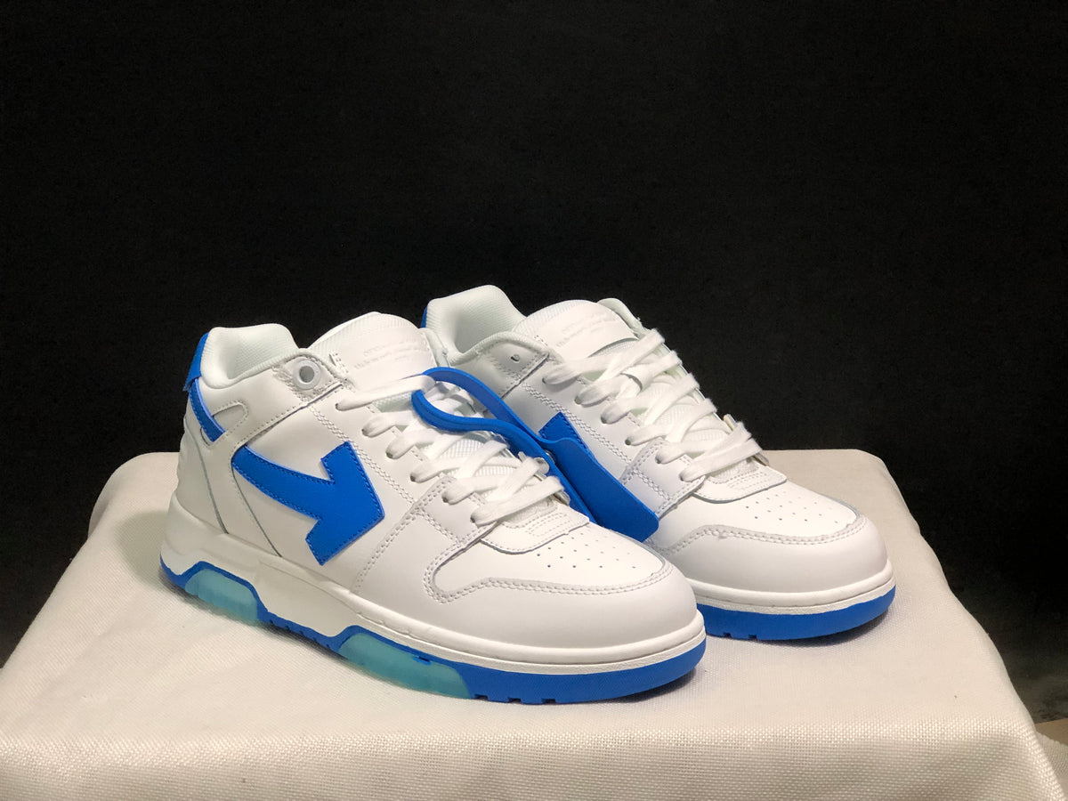 Three-quarter front view of the paired white and blue low-top sneakers with blue tag accessory.