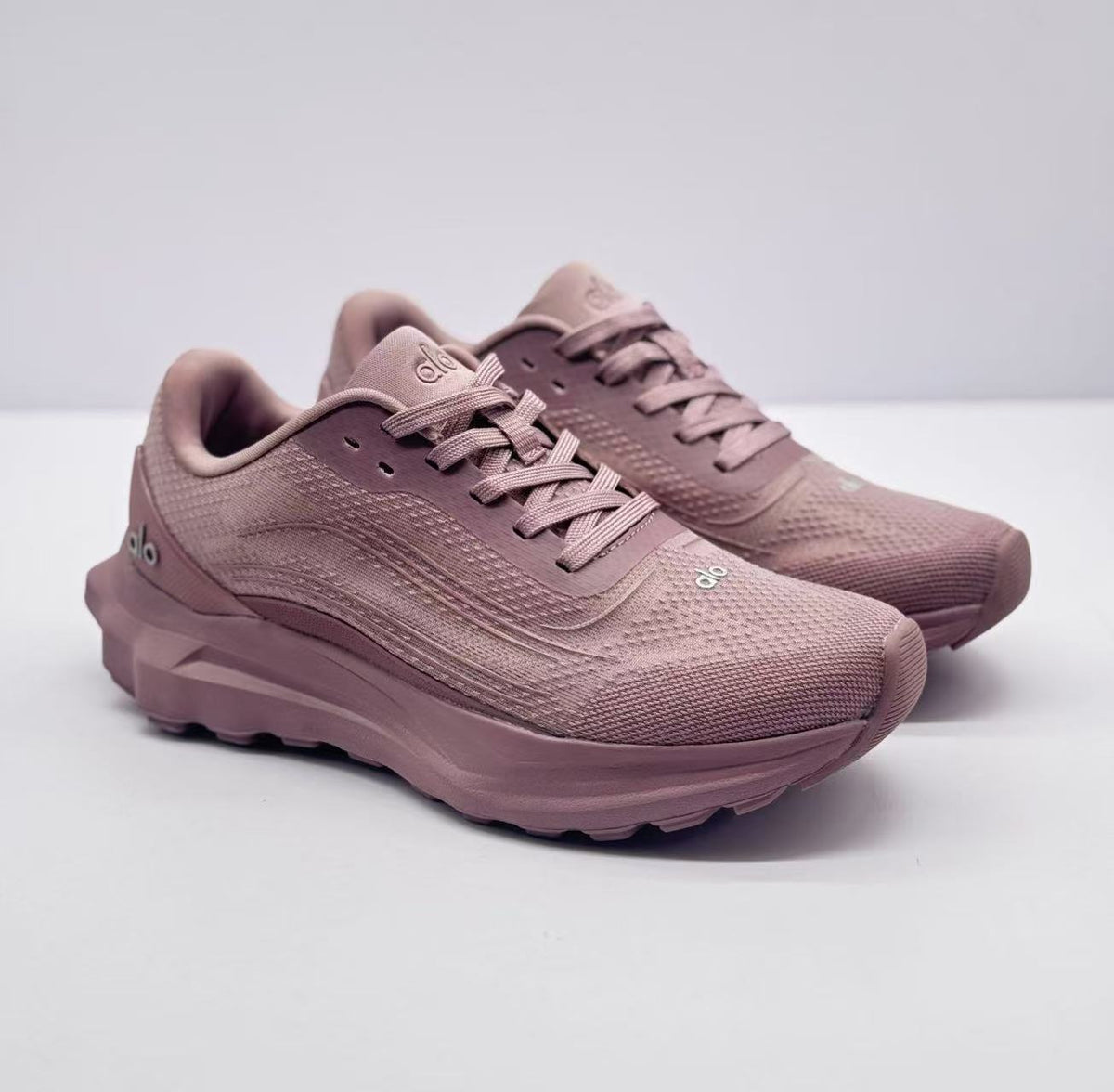 Pair of pink alo sneakers shown from a front three-quarter angle.