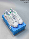 White and green Adidas Stan Smith sneakers shown on a blue shoe box