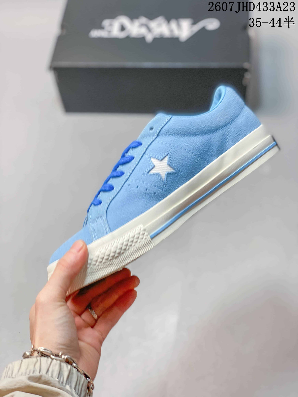 Side profile of the light blue low-top sneaker showing the white star detail, blue accent line and textured rubber outsole.