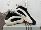 Pair of black sneakers with white sculpted side frames and red accents