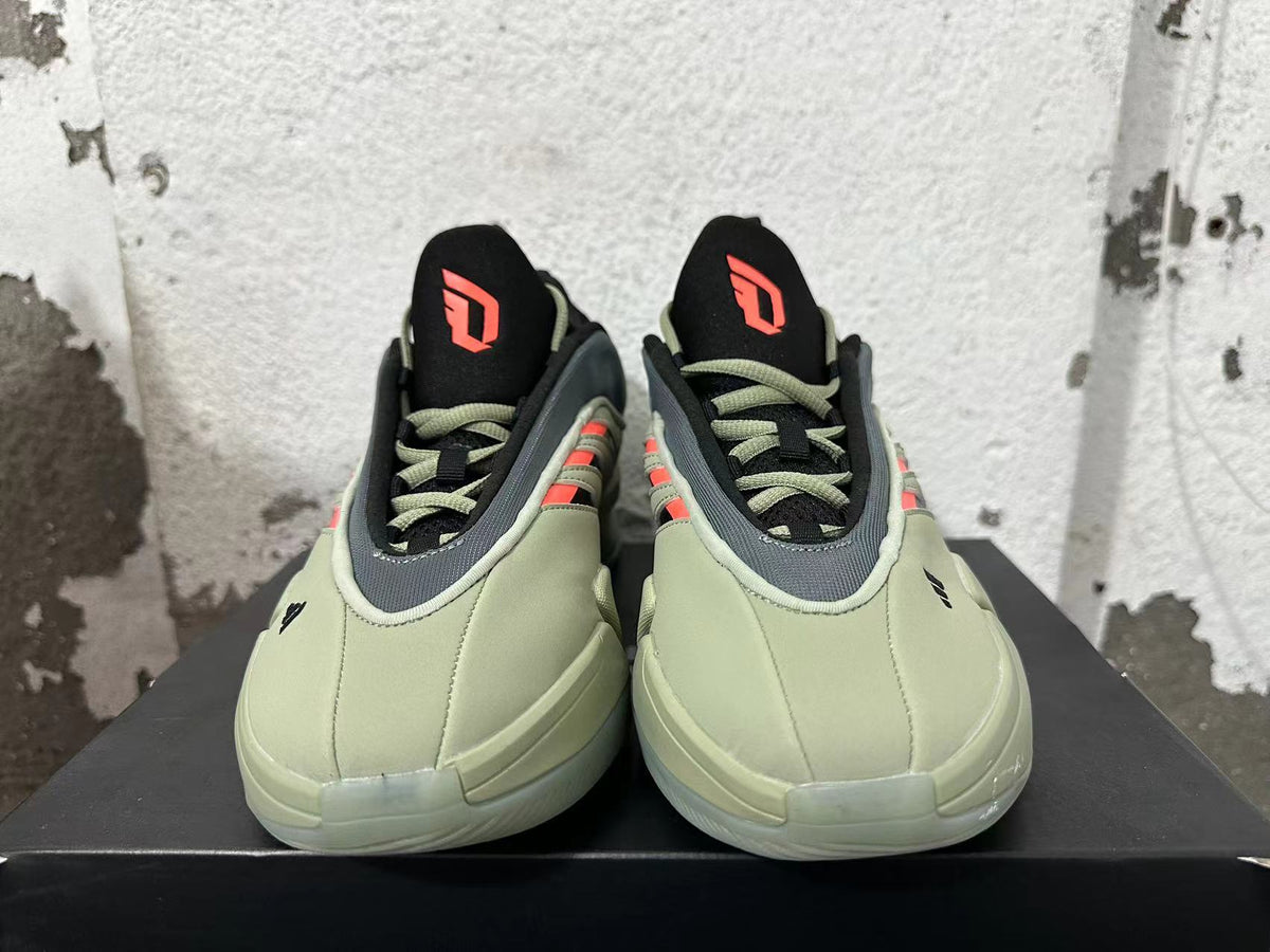 Front view of the green and grey adidas Dame 9 shoes, showing orange tongue logos and matching laces.