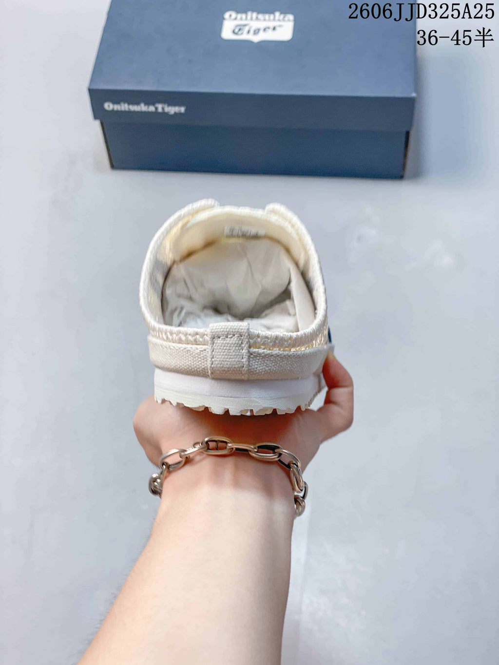 Rear view of the cream slip-on sneaker showing the padded heel collar and outsole edge.