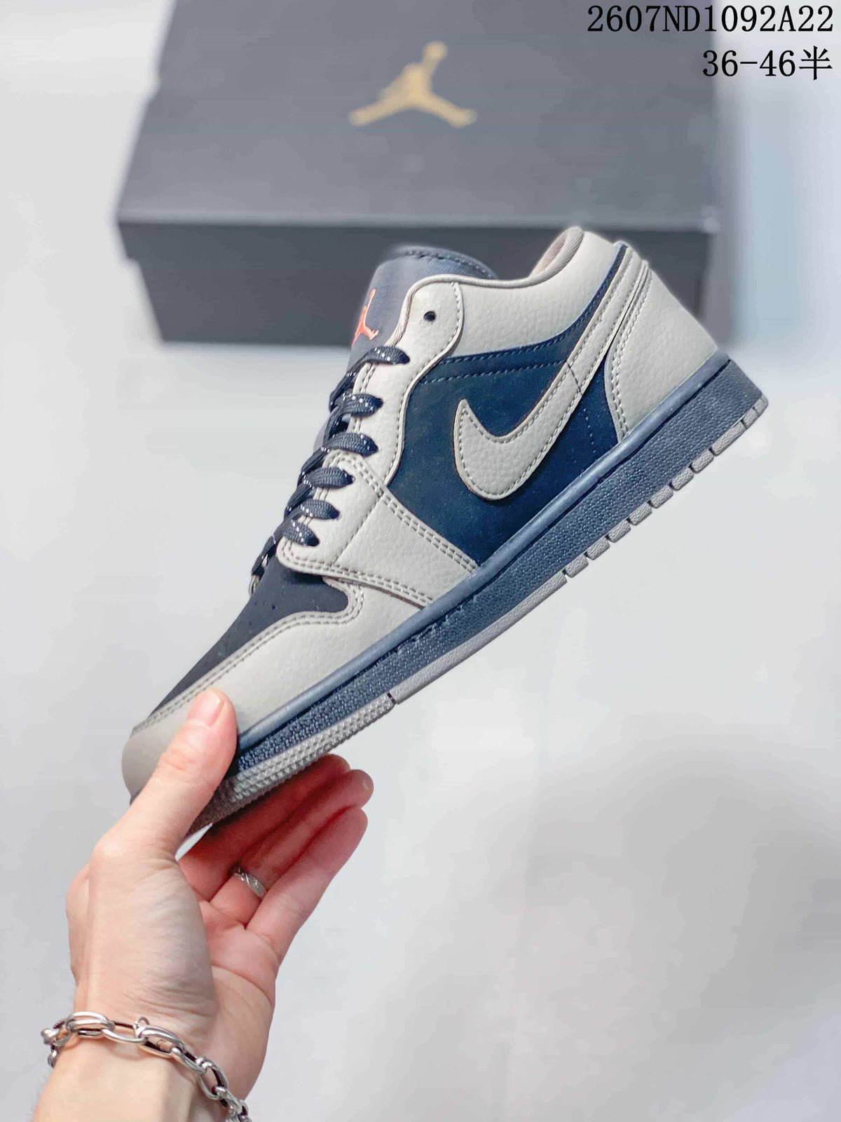 Side profile of a gray and navy low-top sneaker showing the contrasting Swoosh, layered panels, laces, and textured outsole.