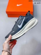 Side profile of the Nike Vomero 18 showing the dark textured upper, large white Swoosh, raised light-colored midsole, and rubber outsole.