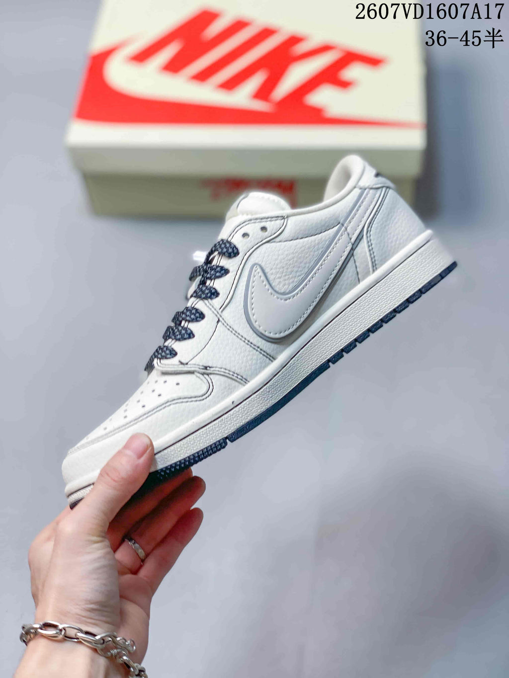 Side profile showing the off-white upper, layered gray side detailing, perforated toe box and dark outsole edge.