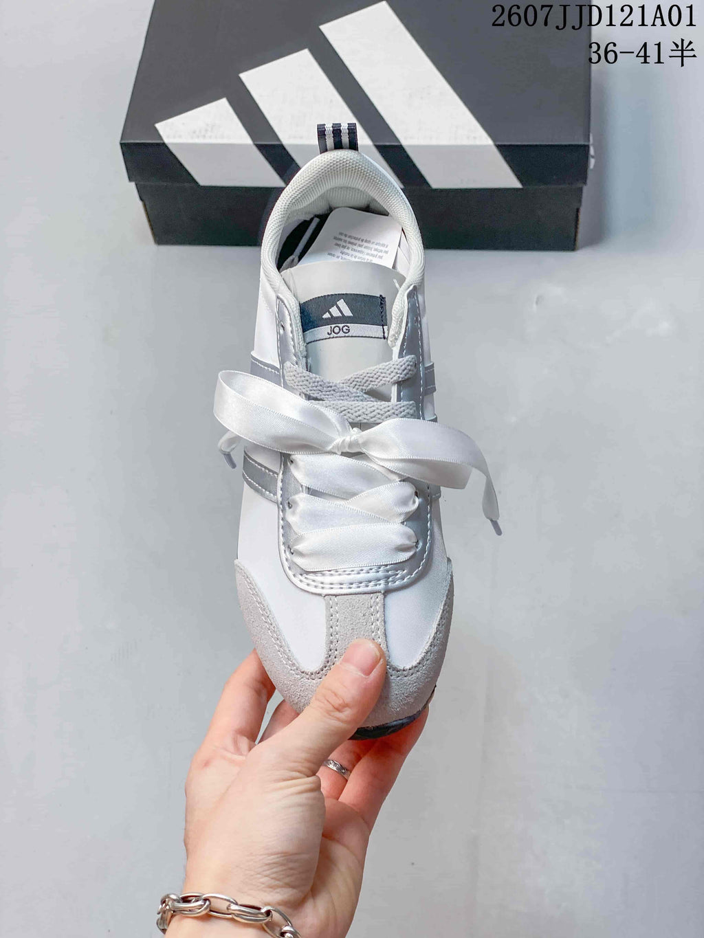 Top view of a white and gray sneaker with wide ribbon laces