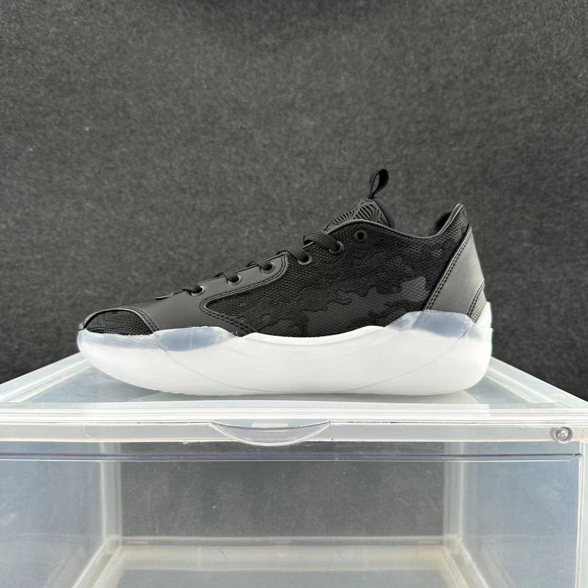 Black Jordan 39 low-top sneaker with patterned side panels and a white sculpted sole, shown from the side.
