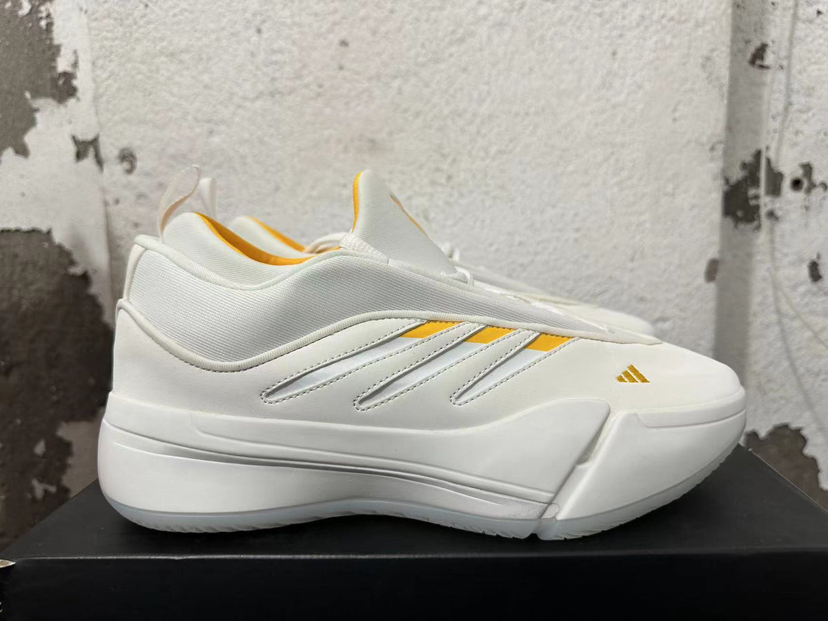 Side view showing white Adidas Dame 9 shoes with yellow accent stripes