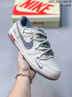 Side view of an off-white and grey low-top sneaker showing a contrasting Swoosh, layered laces and a red side label.